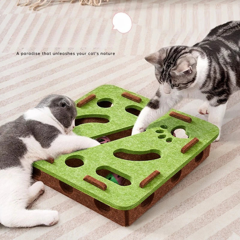 Two cats playing with a green and brown cat puzzle toy on a striped surface.