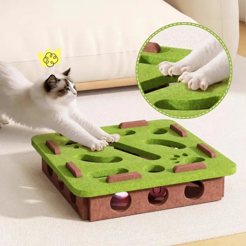 Cat playing with a green and brown cat toy on a white surface.
